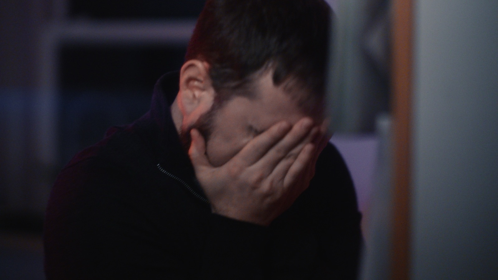 Man covering his face with his hand in dark moody lighting for Cluedo commercial