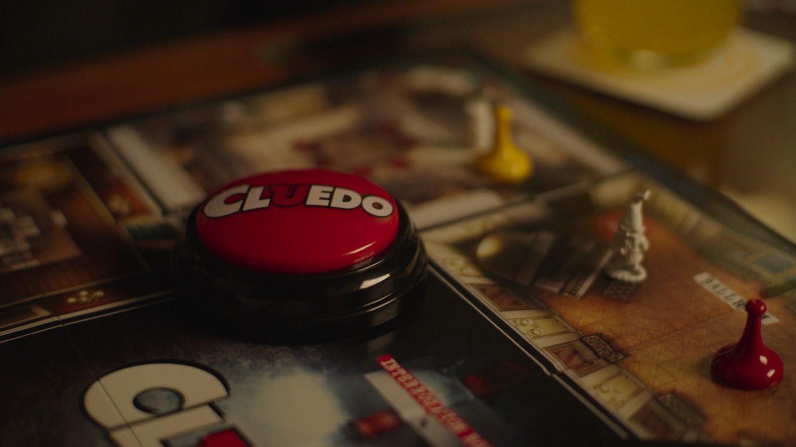 Close-up of Cluedo board game red button with game pieces on the board